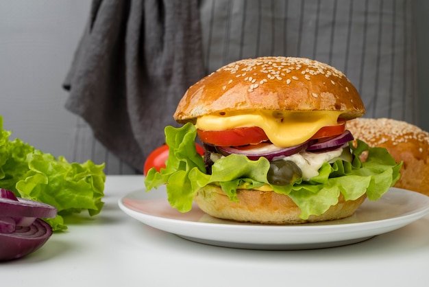 Lateral view tasty cheeseburger on white table