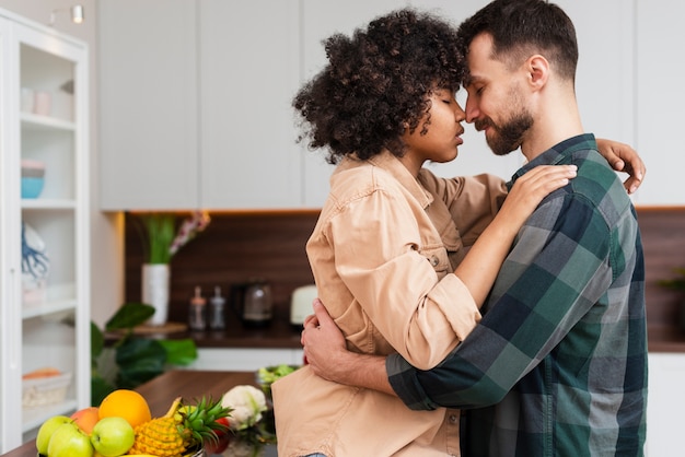 Lateral view young couple embracing in kitchen