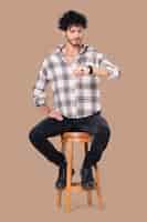 Free photo latin man sitting on a stool while checking the time