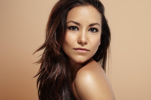 Latin woman with ideal skin on a beige background looking at camera