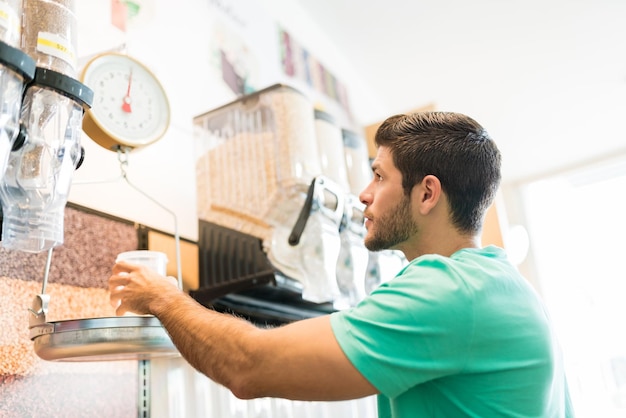 Latin young male customer weighing food in supermarket