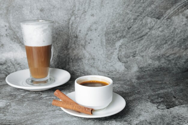 Latte and cup of coffee with cinnamon sticks