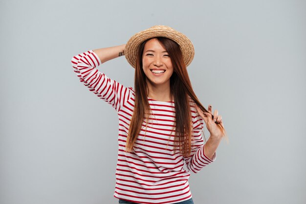 セーターと帽子のカメラ目線でアジアの女性を笑ってください。