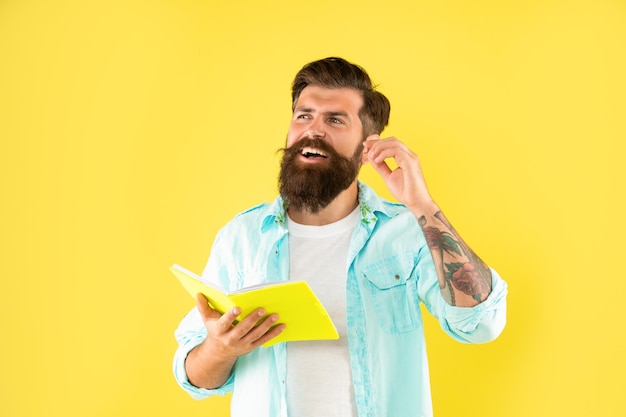 Смеющийся бородатый мужчина с книгой на желтом фоне, эмоции