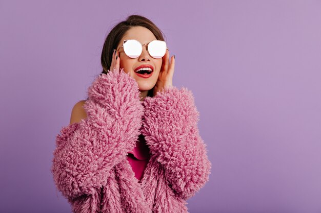 Laughing brunette woman touching her sunglasses