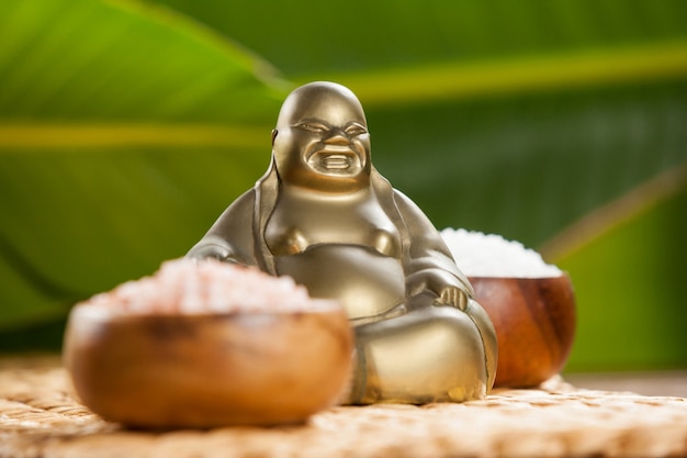 Бесплатное фото laughing buddha фигурку и морскую соль в деревянной миске
