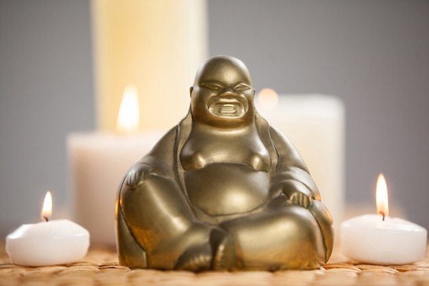 laughing buddha figurine and lit candles on mat