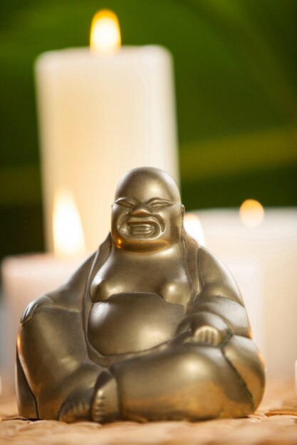 laughing buddha figurine and lit candles on mat