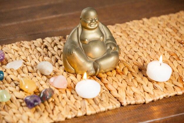 Laughing buddha figurine, pebbles stone and lit candles