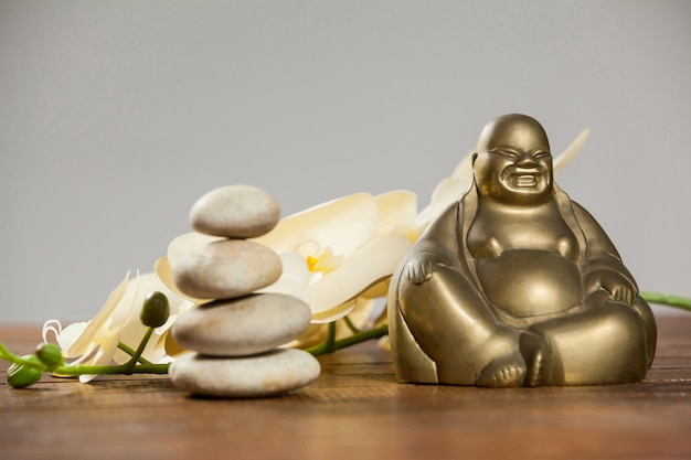 Laughing buddha figurine with pebbles stone and flower