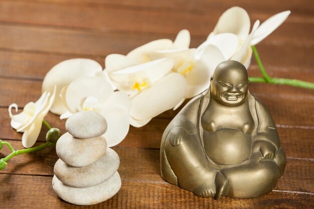 Laughing buddha figurine with pebbles stone and flower