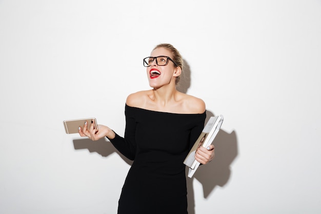 Laughing business woman in dress and eyeglasses looking up