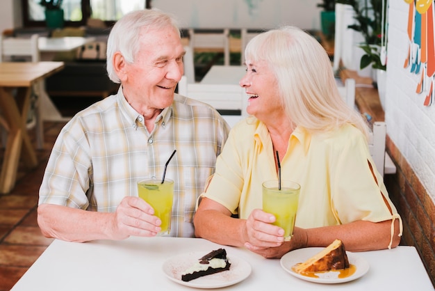 Free photo laughing celebrating elderly couple in cafe