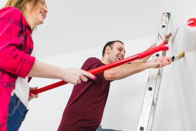 Laughing couple painting wall