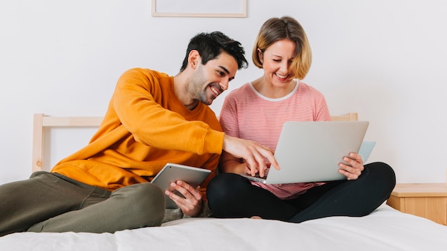 Laughing couple using laptop on bed