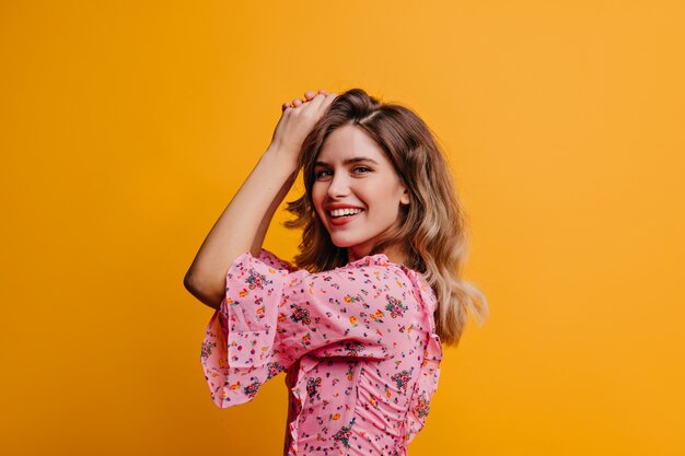 Laughing debonair caucasian girl. Attractive female model expressing positive emotions on yellow wall.