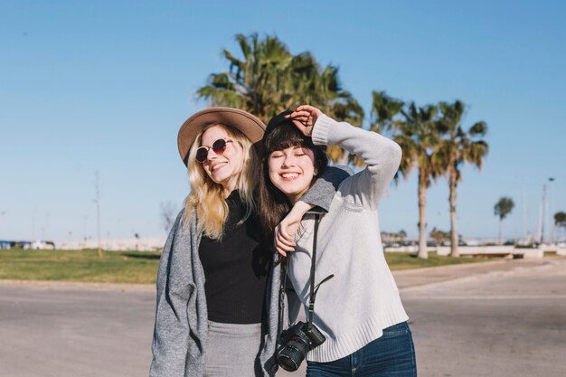 Laughing embracing best friends on street