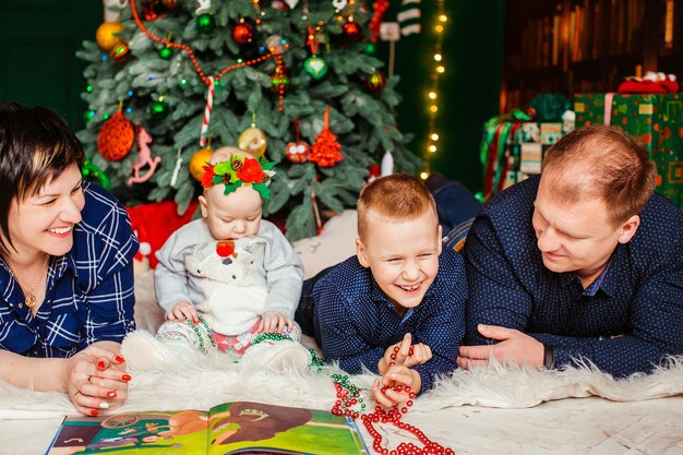 Laughing family lies before fancy Christmas tree 