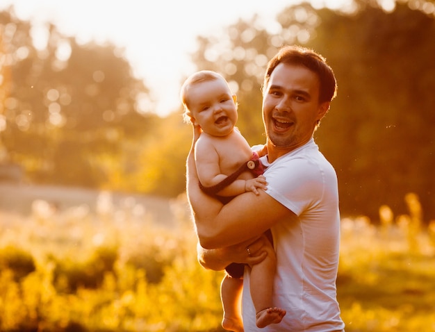 Laughing father holds beautiful child in his arms 