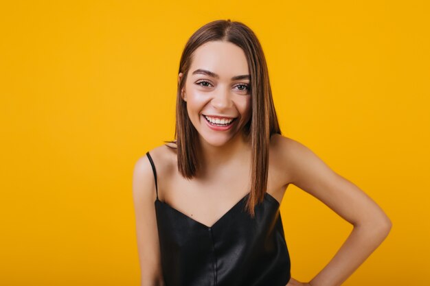 Laughing female model in black tank-top isolated. Portrait of carefree brunette woman with pretty smile.