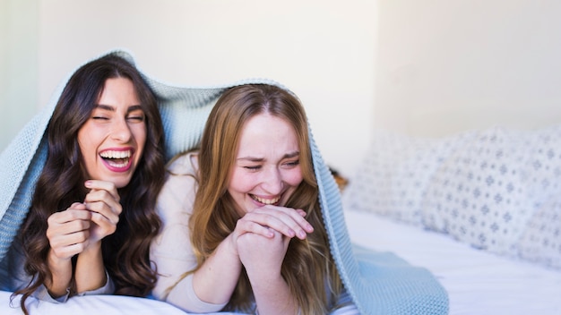 Free photo laughing friends under blanket