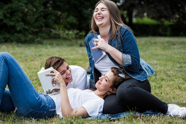 Laughing friends with books in park
