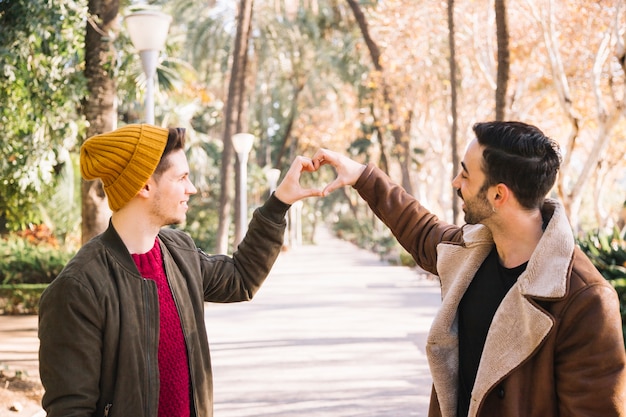 Foto gratuita coppie gay di risata che mostrano cuore con la mano