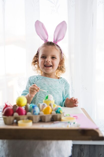 Laughing girl painting eggs