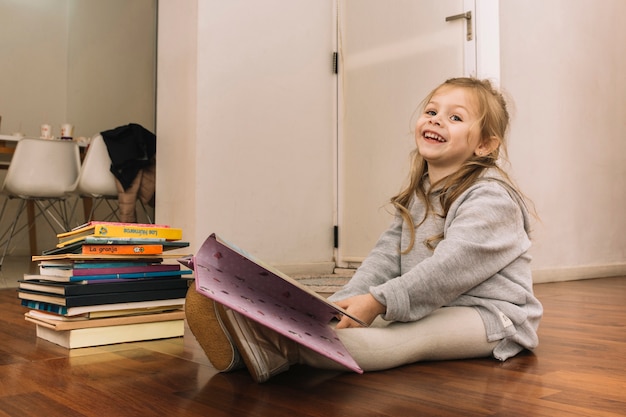 Foto gratuita ragazza che ride leggendo libri sul pavimento