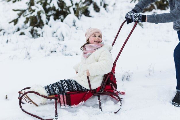 Laughing girl riding sleigh with father