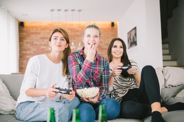 Laughing girlfriends playing videogame and having party