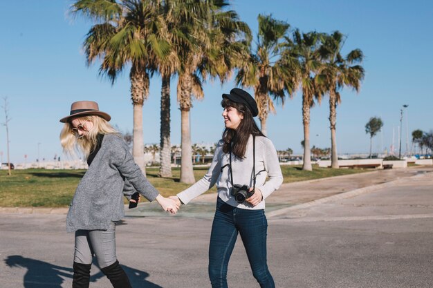 Laughing girls holding hands strolling in sunlight