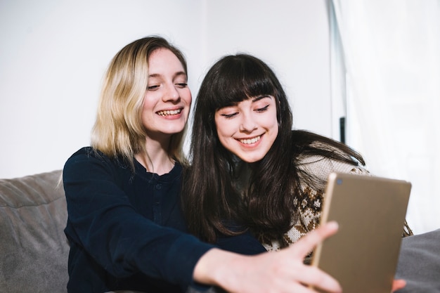 Laughing girls taking selfie at home