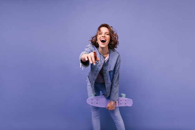 身も凍るような笑いの女の子。スケートボードを楽しんでいる興奮したトレンディな女性。