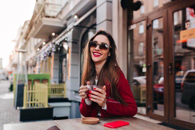 Laughing gorgeous woman with straight dark hair posing in street cafe