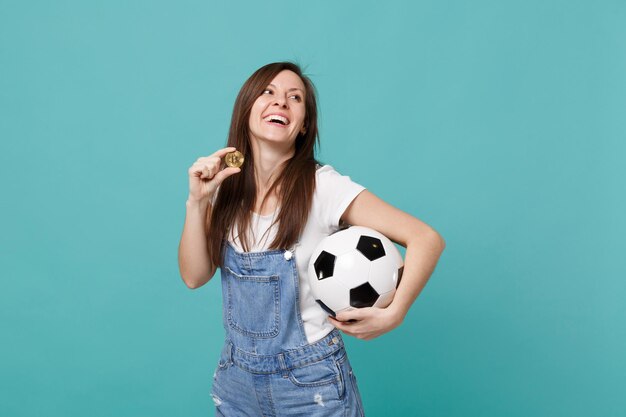 웃고 있는 행복한 젊은 여성 축구 팬은 축구공으로 좋아하는 팀을 지원하고, 파란색 청록색 배경에 격리된 비트코인 미래 통화입니다. 사람들의 감정, 스포츠 가족 레저 라이프 스타일 개념.