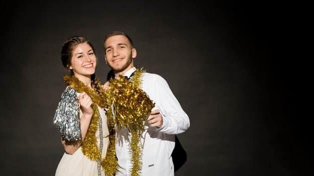 Laughing lady and guy in evening wear with tinsel