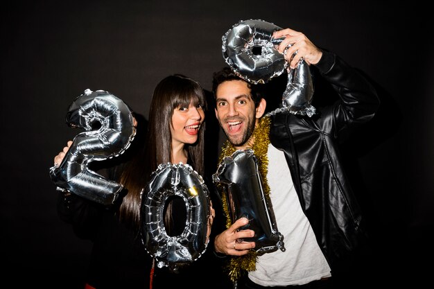 Laughing lady and guy with tinsel and balloons numbers 