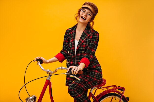 Смеющаяся дама в клетчатой куртке на велосипеде