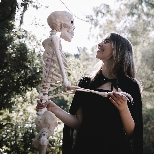 Laughing lady in witch clothes holding skeleton