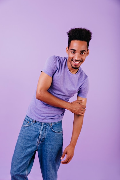 Free photo laughing lovable man in jeans posing. indoor photo of african male model with trendy haircut standing.