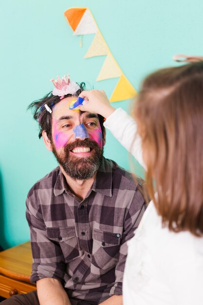 Laughing man with daughter painting face