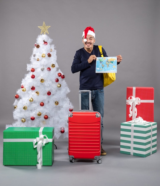 laughing man with red suitcase holding map with both hand on grey isolated