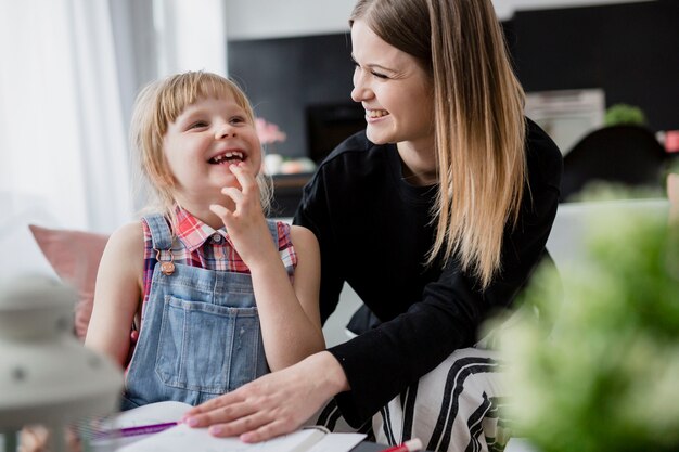 Laughing mother and daughter doing homework