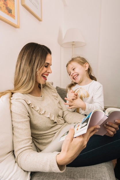 Free photo laughing mother and daughter reading comics