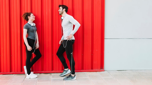 Laughing people communicating near red wall