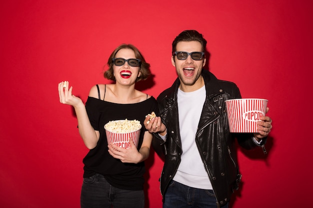 Laughing punk couple eating popcorn and looking