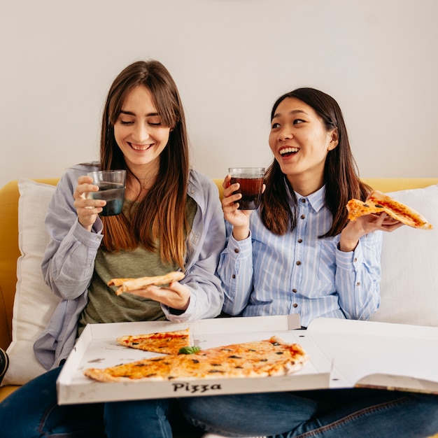 Laughing relaxing girls enjoying pizza