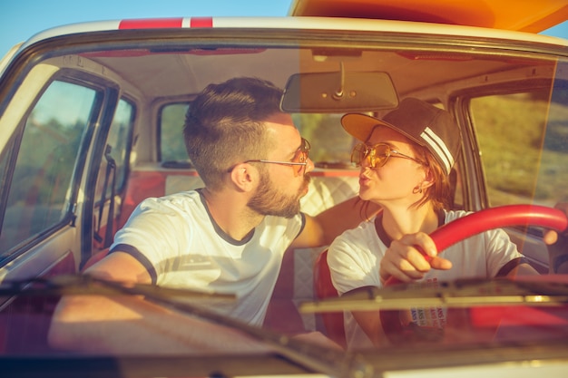 ロードトリップ中に車の中で座って笑うロマンチックなカップル。