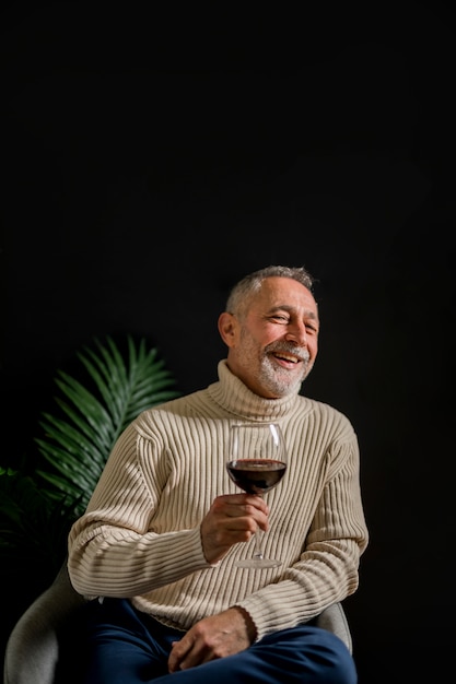 Смеющийся старший мужчина с бокалом вина